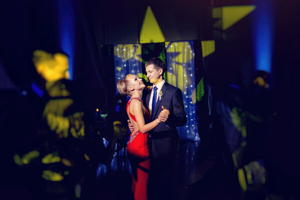 стильная роскошная невеста в красном платье и жених танцует в ресторане
