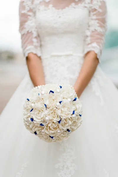 Neobvyklé měkké bílé svatební kytice v ruce nevěsty — Stock fotografie
