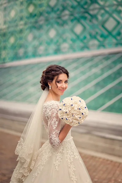 happy bride with unusual bouquet on the background of modern gla
