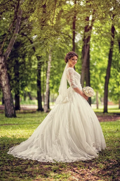 Elegante novia en vestido de novia con dobladillo sumergido en longitud completa en — Foto de Stock
