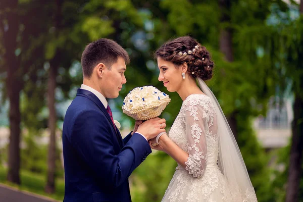 Verliebte Braut und Bräutigam schauen einander mit einem Strauß an — Stockfoto