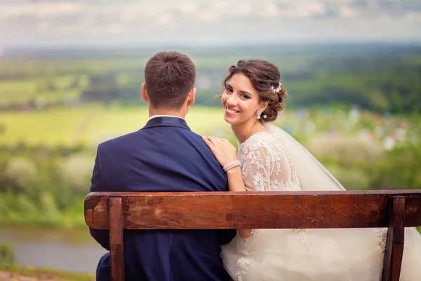 Portrait d'une mariée heureuse assise sur un banc sur le dessus du h — Photo