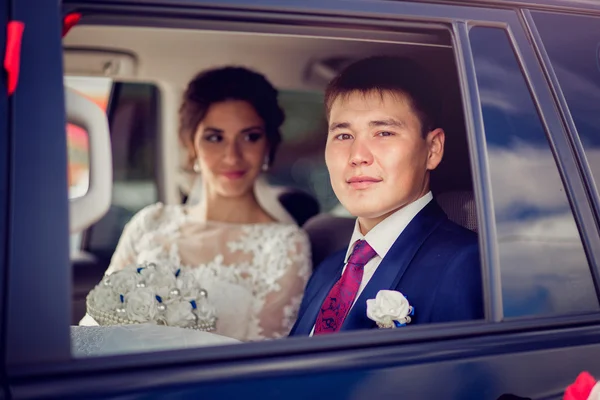 Portrait rapproché de jeunes mariés heureux dans une fenêtre de voiture — Photo