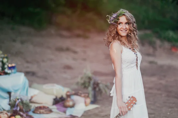 Chica en un picnic de verano en un vestido de sol y una corona de harinas silvestres — Foto de Stock