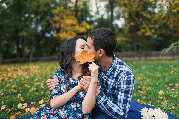 Jong liefdevol paar zoenen achter groot blad, verborgen kus — Stockfoto