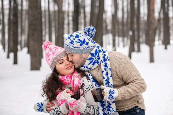 Casal feliz com cobertor quente beber chá quente em uma floresta nevada — Fotografia de Stock