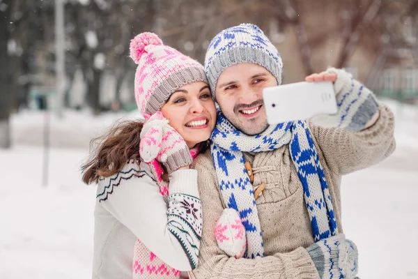 Par i kärlek att göra selfie på vintern utomhus i tröjor, halsduk och vantar — Stockfoto