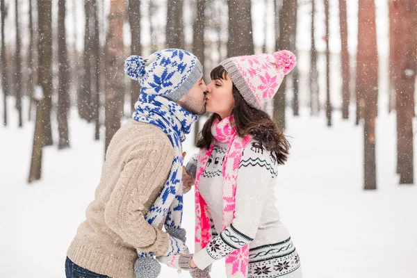 Glad ung man och kvinna kysser i snöiga skogen — Stockfoto