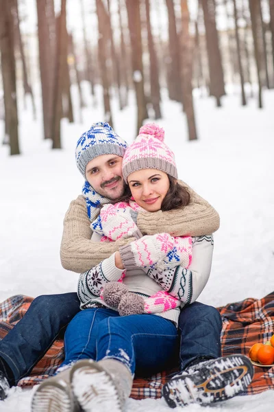 Casal apaixonado abraçando no parque de inverno e sentado no pla — Fotografia de Stock