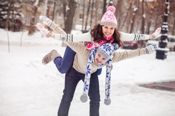 Gelukkige jonge paar wandelen in winter park piggyback — Stockfoto
