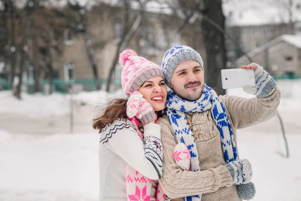 Пара закохана посміхається і робить селфі взимку на відкритому повітрі — стокове фото