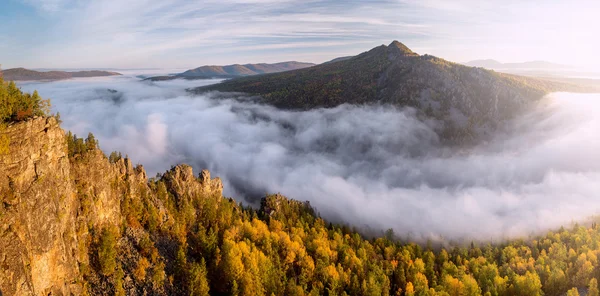 Berg im Morgennebel und umgeben von niedrigen Wolken — Stockfoto