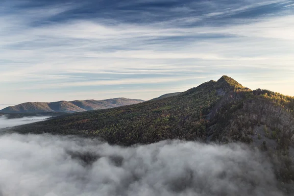 Berg i morgondimman och omgiven av låga moln — Stockfoto