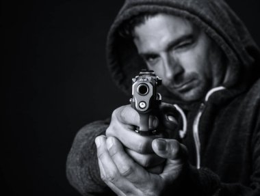 Genç beyaz adam silah doğrultuyor, namluya odaklanıyor..