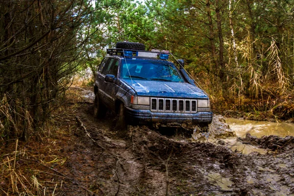 Offroad arabası iş başında. Kirli araç bataklıktan çıkıyor.