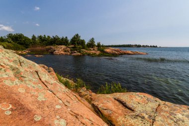 Huron Gölü boyunca uzanan granit kıyı şeridi. Kanada, Ontario 'daki Killarney İl Parkı' ndaki Gürcistan Körfezi 'ndeki Chikanishing Deresi' nin ağzındaki granit kayalar.