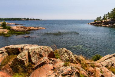 Huron Gölü boyunca uzanan granit kıyı şeridi. Kanada, Ontario 'daki Killarney İl Parkı' ndaki Gürcistan Körfezi 'ndeki Chikanishing Deresi' nin ağzındaki granit kayalar.