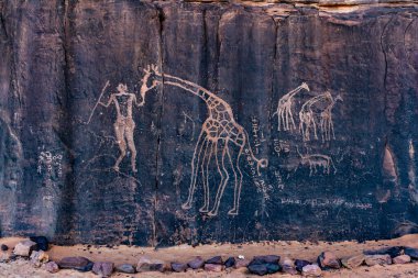 Neolitik kaya sanatı. Bir insan ve zürafayı tasvir eden tarih öncesi kaya oymacılığı. Wilaya Tamanrasset, Hoggar Dağları, Tassili nAjjer Ulusal Parkı, Güney Cezayir, Afrika,