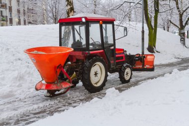 Bir traktör ve kumluk ile küçük bir kar küreme aracı karı temizler ve Katowice, Silezya, Polonya gibi bir konut arazisinin sokaklarına tuz sürer.