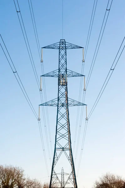 早朝の青い空に照りつける高電圧送電線 — ストック写真
