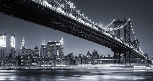 Manhattan Skyline and Manhattan Bridge At Night. Manhattan Bridge is a suspension bridge that crosses the East River in New York City. Long exposure for night image.