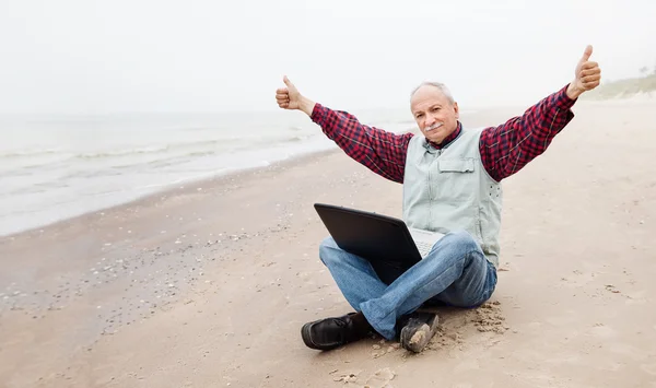 Yaşlı adam sahilde defter ile — Stok fotoğraf