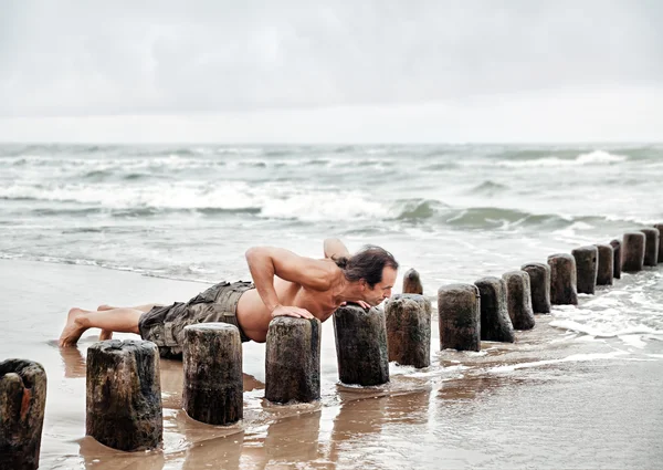 Hombre hace ejercicios deportivos en la playa — Foto de Stock