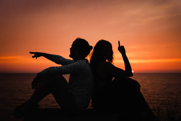 Young couple in love against sunset at sea — Stock Photo, Image