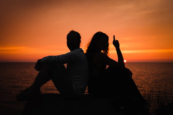 Jong koppel in liefde tegen zonsondergang op zee — Stockfoto