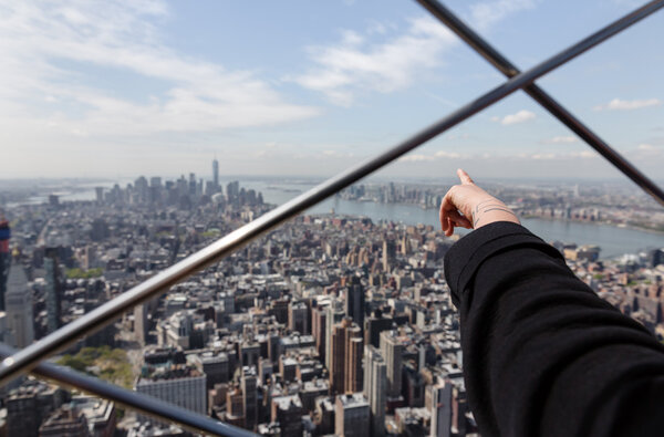 NEW YORK, USA - Apr 30, 2016: Tourists enjoying the breathtaking views of New York City from the observation deck of Empire State Building. Focus on finger