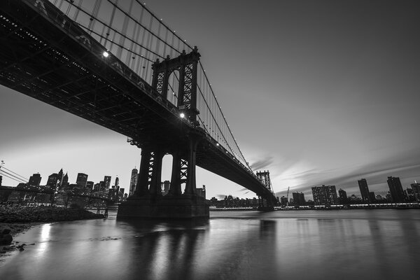 Black and White Image of Manhattan Skyline and Manhattan Bridge At Night. Manhattan Bridge is a suspension bridge that crosses the East River in New York City
