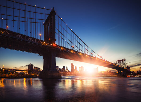 Manhattan Skyline and Manhattan Bridge at Sunset. Manhattan Bridge is a suspension bridge that crosses the East River in New York City