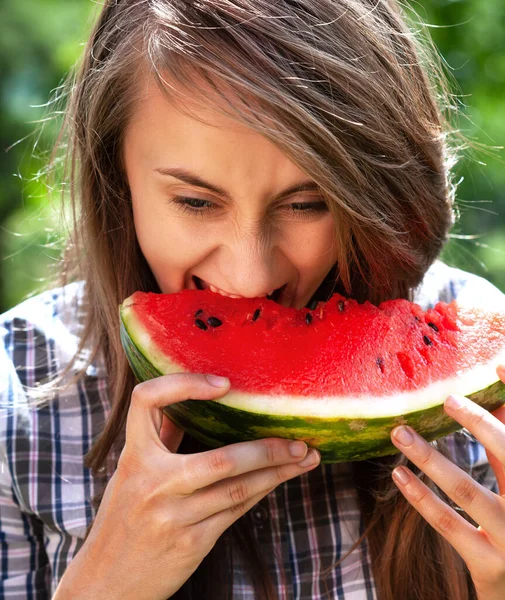 健康的な食べ物と健康的なライフスタイルの概念 若い幸せな女性は自然を背景にスイカのスライスを食べています — ストック写真