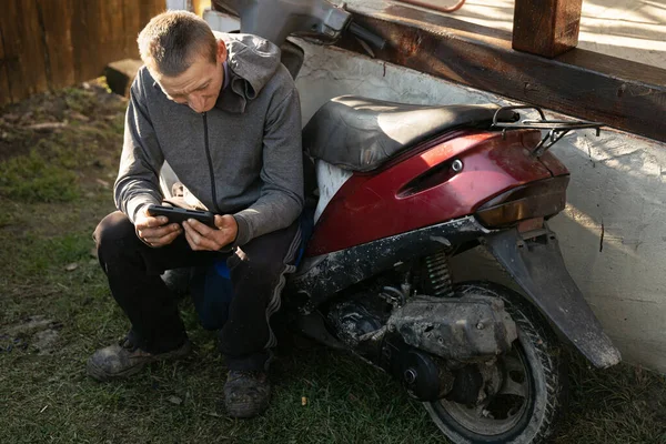 Młody Wiejski Roboczy Facet Odpoczywa Pobliżu Jej Motocykl Zabawy Smartfonem — Zdjęcie stockowe