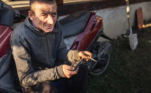 Joven Trabajador Rural Descansando Sentado Cerca Motocicleta Fuma Juega Con —  Fotos de Stock