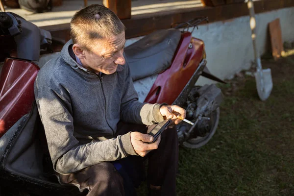 Joven Trabajador Rural Descansando Sentado Cerca Motocicleta Fuma Juega Con — Foto de Stock