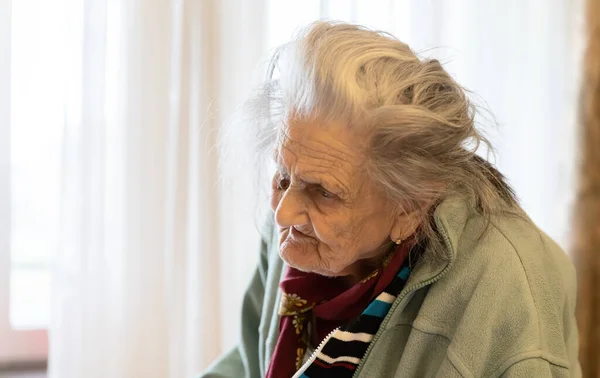 老太婆站在窗前垂头丧气的疲倦老妇人的画像 — 图库照片