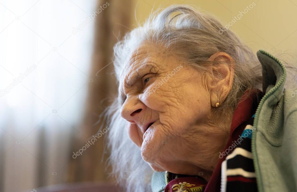 Old woman. Portrait of very old tired woman in depression sitting indoors on bed