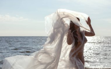 Güzel çıplak kadın vücudu plastiğin altında, arka planda. Rüzgarlı bir günde deniz kenarında polietilen bir filmin arkasındaki seksi kız. Güzel sanatlar fotoğrafı..
