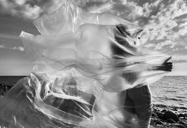 Güzel çıplak kadın vücudu plastiğin altında, arka planda. Rüzgarlı bir günde deniz kenarında polietilen bir filmin arkasındaki seksi kız. Güzel sanatlar fotoğrafı..