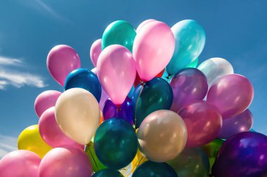 Mavi gökyüzü arka planında bulutlu bir sürü renkli balon