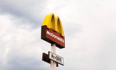 KYIV, UKRAINE - Nisan. 27, 2021: Küresel fast food restoran zinciri McDonalds logosu bulutlu mavi gökyüzüne karşı