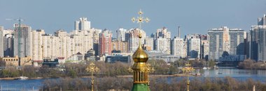 KYIV, UKRAINE - Nisan. 28, 2021: Vydubychi Manastırı. Hristiyan manastırı kubbeleri. Botanik bahçesinden Kyiv şehir manzarası. Dinyeper nehri ve büyük şehrin yeni binaları