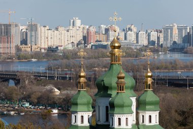KYIV, UKRAINE - Nisan. 28, 2021: Vydubychi Manastırı. Hristiyan manastırı kubbeleri. Botanik bahçesinden Kyiv şehir manzarası. Dinyeper nehri ve büyük şehrin yeni binaları