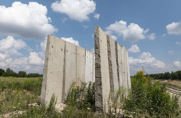 Old concrete slabs standing on a summer sunny day in the field. Old unfinished building