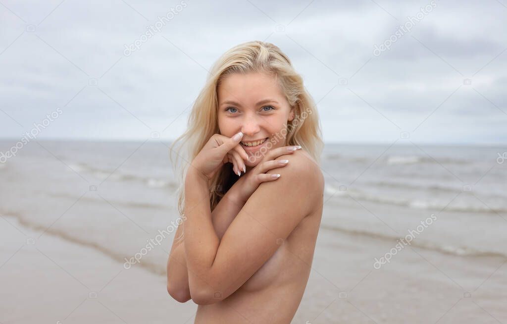 Portrait of a young naked woman on nature background. Outdoor portrait of beautiful young blonde woman on seashore