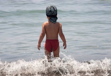 Deniz kıyısında ilk kez küçük bir çocuk temiz havanın ve deniz dalgalarının tadını çıkarıyor.