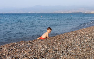 Sağlıklı bir yaşam tarzı. Küçük çocuk dinleniyor ve Akdeniz kıyısındaki kayalık bir sahilde eğleniyor.
