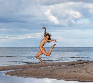 Sahilde atlayan çıplak bir kadın. Doğanın tadını çıkaran güzel bir kız. Yaz aktiviteleri ve kadın uçuşları. Atlayan bir kızın ekstra mutluluğu.