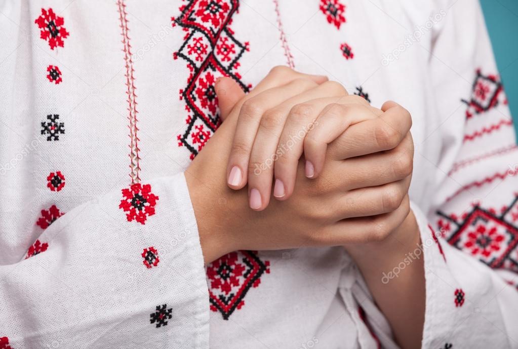 Hands of a young woman in the Ukrainian national clothes